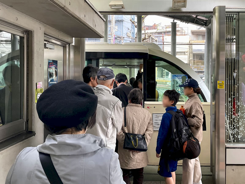 飛鳥山公園へ上るモノレールに乗車しようとしている人々